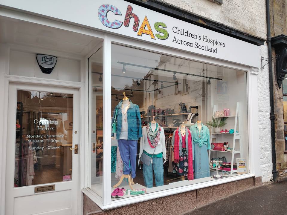CHAS (Children’s Hospices Across Scotland) Bazaar 2 charity shop window display featuring mannequins dressed in colorful clothing, accessories, and various items for sale.